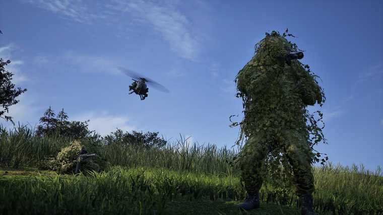A sniper in a ghillie suit crouched in tall grass with a drone hovering overhead